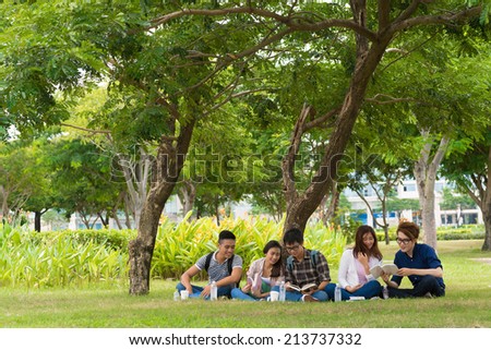 Vietnamese students sitting in the park and studying together