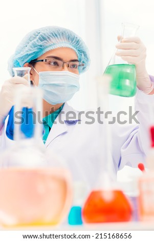Young laboratory working looking at flask in her hand