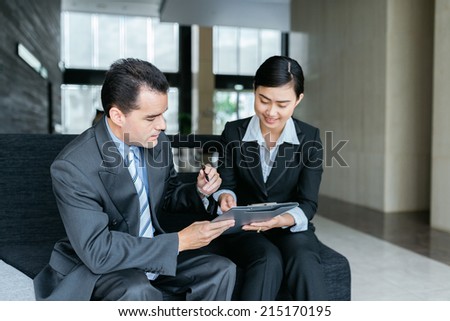Young manager showing her business partner where to sing the document