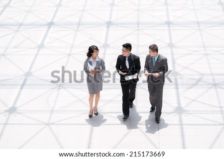 Asian managers walking and discussing documents, view from above