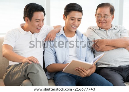 Grandfather, son, and grandson reading a book together