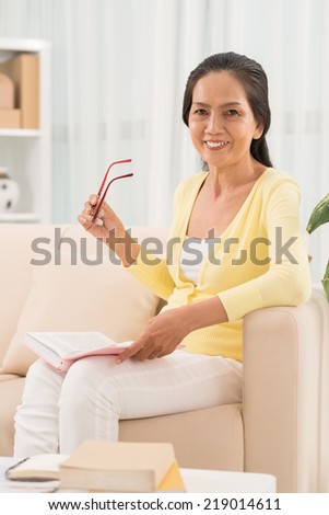 Portrait of Asian woman sitting on the sofa with opened boob on her knees