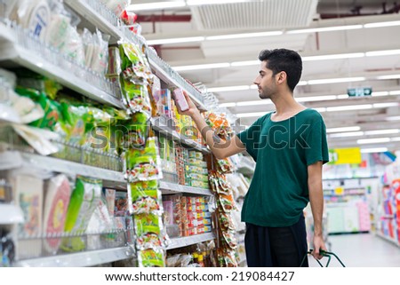 Handsome young man buying instant food in the supermarket