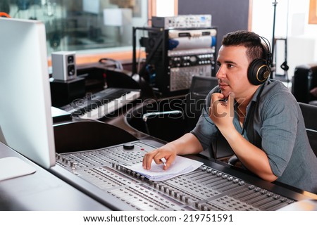 Hispanic sound engineer working at mixing panel in the recording studio
