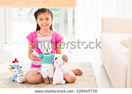 Child playing with handmade knitted toys sitting on the floor