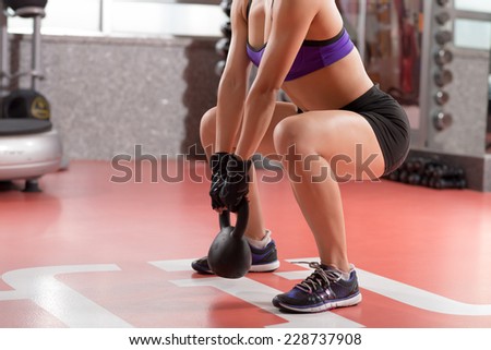 Cropped image of professional sportswoman doing kettlebell weight exercise