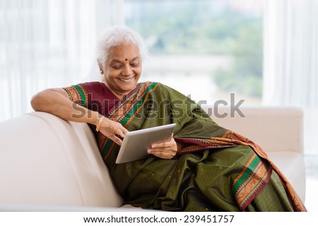 Indian woman in national dress sitting on the sofa and using a tablet