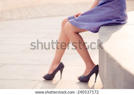 Beautiful legs of woman wearing purple heels and dress