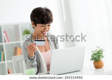 Happy senior woman using laptop to shop online