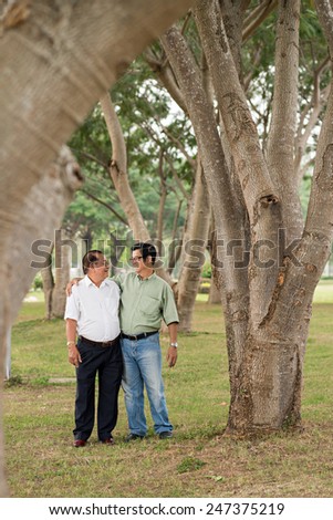 Senior Vietnamese men talking while walking in the park