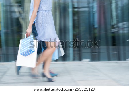 Blurred motion of couple with paper bags walking along the street