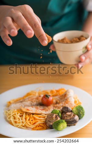 Cropped image of Indian cook sprinkling the dish with some spices
