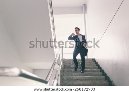 Businessman walking down the staircase and checking time