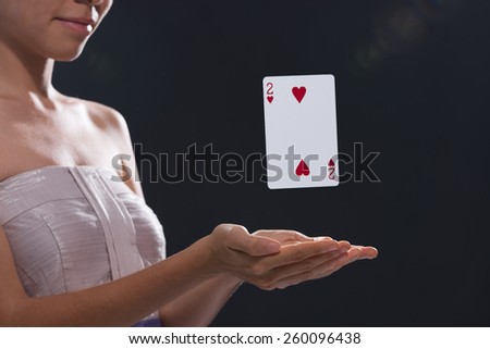 Woman using magic to make playing card levitate