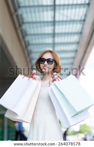 Pretty girl in sunglasses holding many shopping bags
