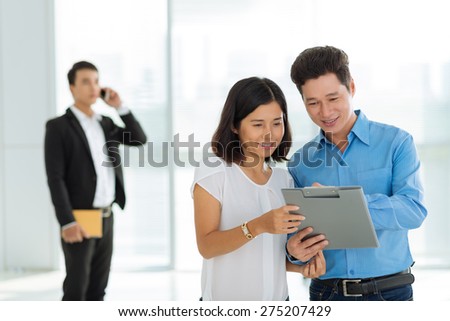 Happy family reading real estate purchase contract while broker talking on the phone in the background