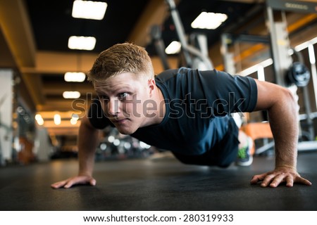 Handsome man doing push-ups in sports club