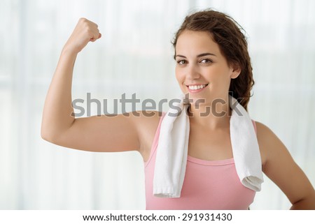 Smiling athletic woman flexing her biceps: fitness and diet concept