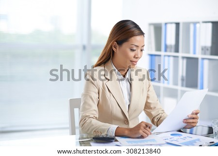 Portrait of smiling Asian business lady working with papers