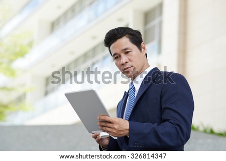 Businessman surfing the net on touchpad outdoors