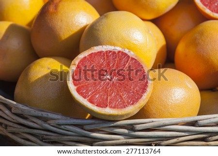 Ripe juicy grapefruits on a show-window of shop of vegetables and fruit and a grapefruit half