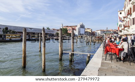 VENICE, ITALY - on APRIL 29, 2015. People have a rest and eat in summer cafe on the bank of the Grand channel (Canal Grande).