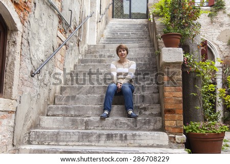 VENICE, ITALY - on MAY 1, 2015. The woman sits on steps of an old stone ladder