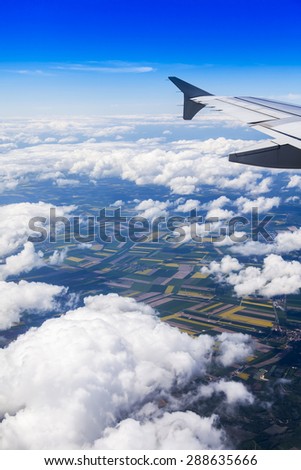 Plane view from the window on picturesque landscape with white clouds