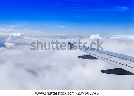 Plane view from the window on picturesque white clouds and wing of the plane