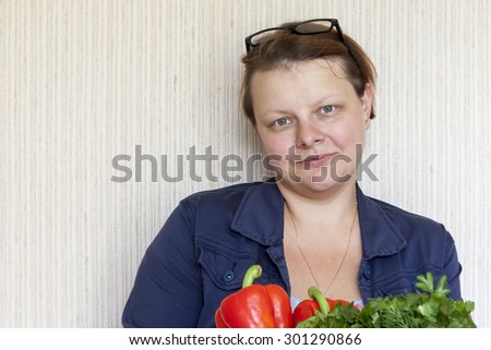 The young woman holds vegetables in hand and smiles
