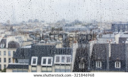 PARIS, FRANCE, on AUGUST 27, 2015. A look through a wet window. to roofs of the city7 It is raining, water drops on glass, focus on drops