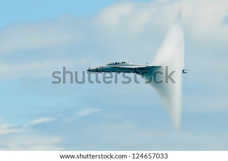 Military plane sound barier.  Military plane on blue, cloudy sky background.