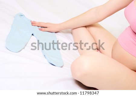 closeup young pregnant woman sitting on the bad  and stroking breeches