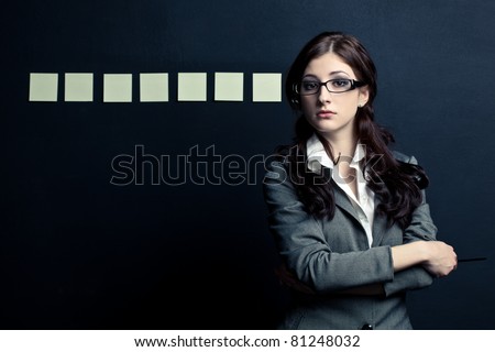 beautiful businesswoman standing near black wall with stickers