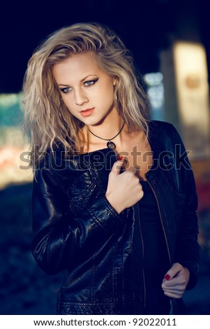 woman looking down wearing leather jacket on ruins. Fashion photo