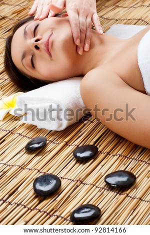 brunette woman in spa salon. Massage of neck and face