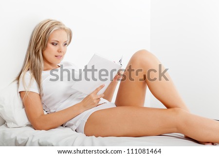 beautiful blonde woman reading book in bed