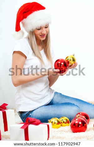 woman wearing santa hat sitting on the floor and looking to the balls