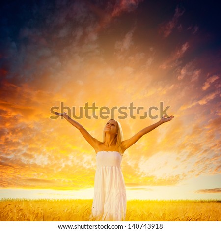 beautiful blonde woman walking on wheat field over beautiful sunset