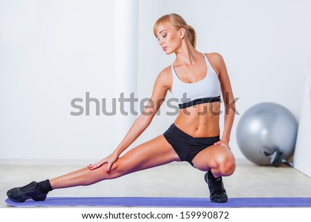 blonde woman stretching muscles on the floor