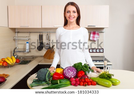 happy smiling young woman with vegetables at kitchen