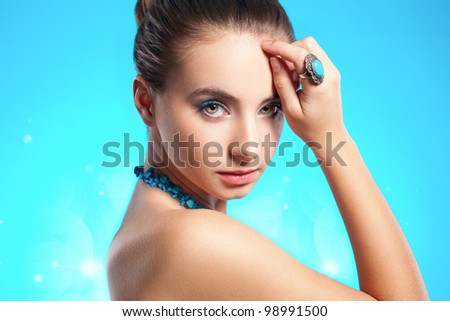brunette woman portrait with turquoise necklace and ring on finger, hand on head