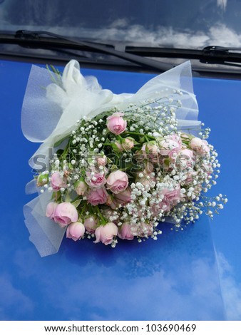 Bouquet of roses on a cowl of the dark blue car.