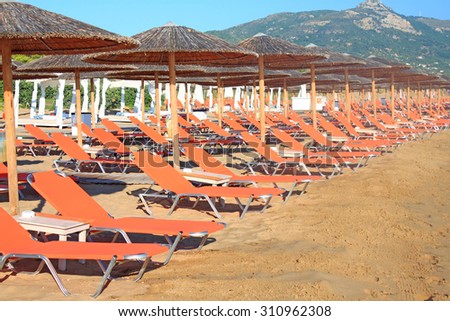 Rows of straw umbrellas and loungers at banana beach, Zakynthos, Greece.