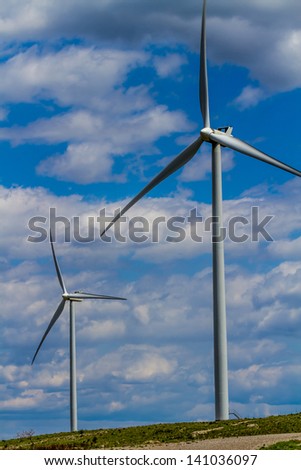 Two Huge High Tech Industrial Wind Turbines Generating Environmentally Sustainable Clean Electricity in Oklahoma.  With Blue Skies and White Clouds.