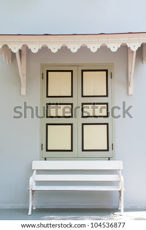 The open window and white bench outside of building.