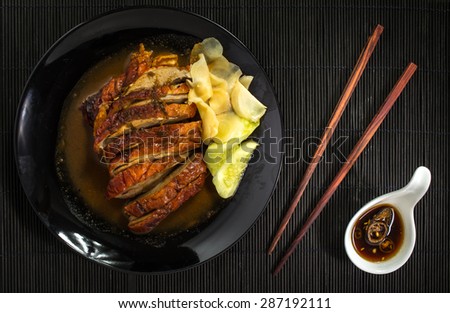 Roast duck and sauces with chopsticks over Black Sushi mat
