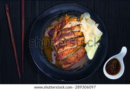 Roast duck and sauces with chopsticks over Black Sushi mat