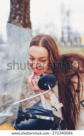 Woman putting red lipstick looking in mirror.