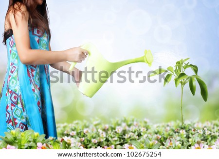 girl watering trees and flowers on a natural background